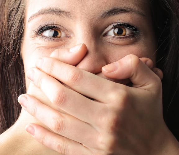 Woman holding both of her hands over her mouth